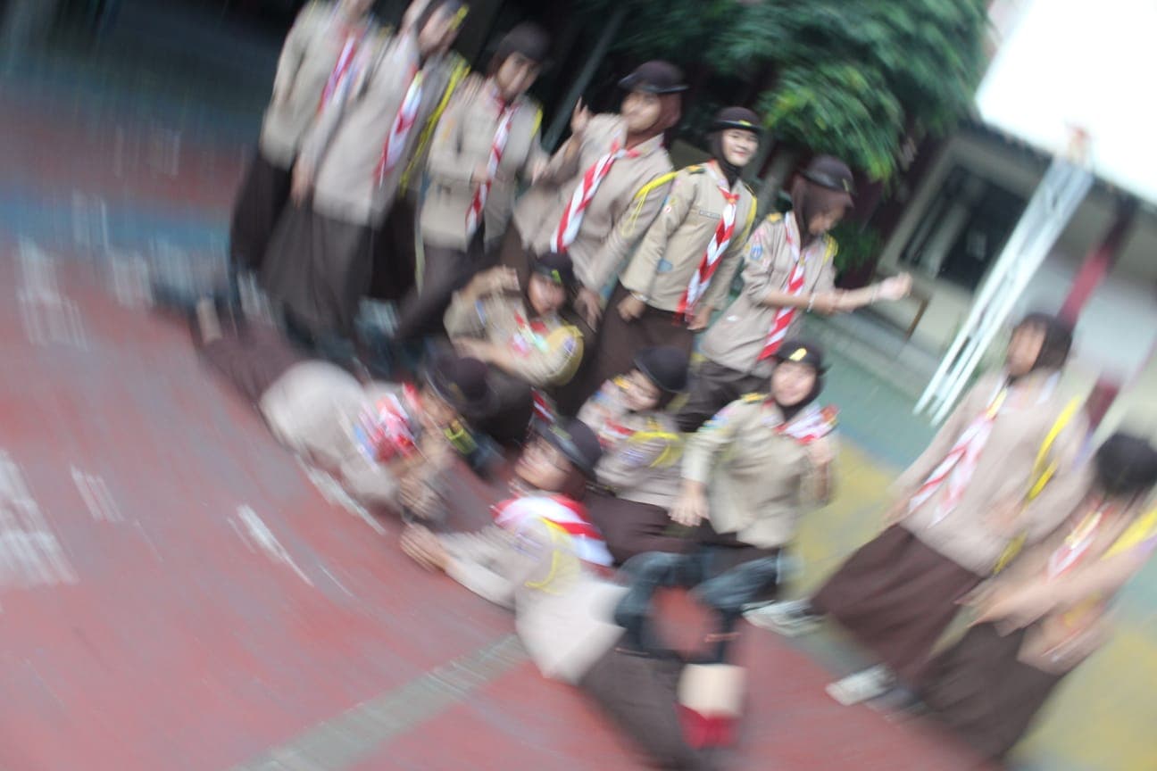 Sekelompok siswa berseragam Pramuka berpose di luar ruangan, foto tampak buram dengan sudut miring.