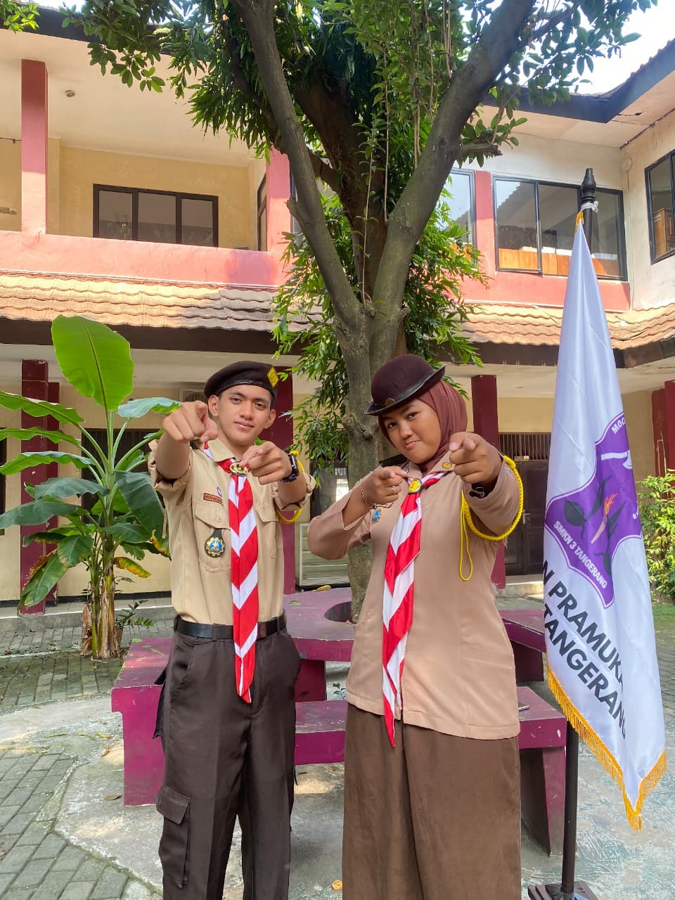 Dua anggota pramuka SMKN 3 Tangerang berpose menunjuk ke arah kamera di halaman sekolah.