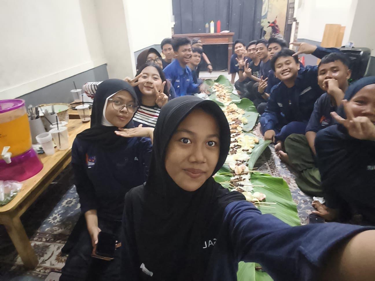 Sekelompok remaja duduk lesehan menikmati hidangan nasi liwet di atas daun pisang sambil berswafoto.