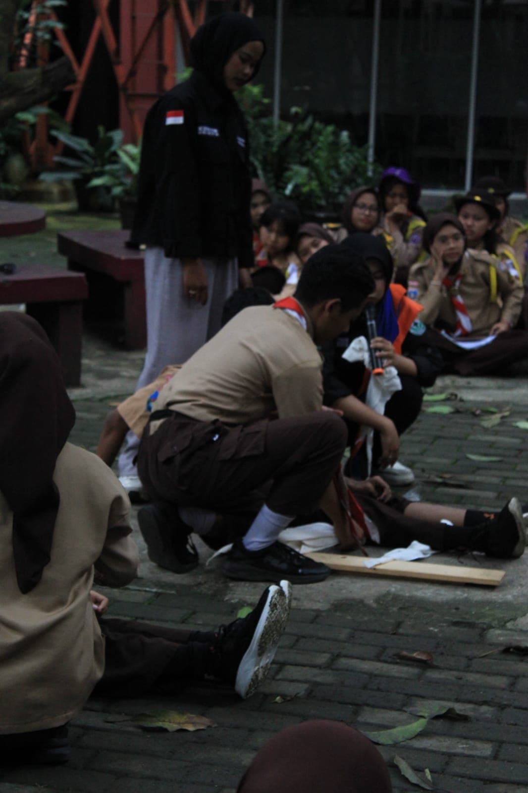 Anggota Pramuka mempraktikkan teknik pertolongan pertama pada korban saat latihan simulasi di luar ruangan.