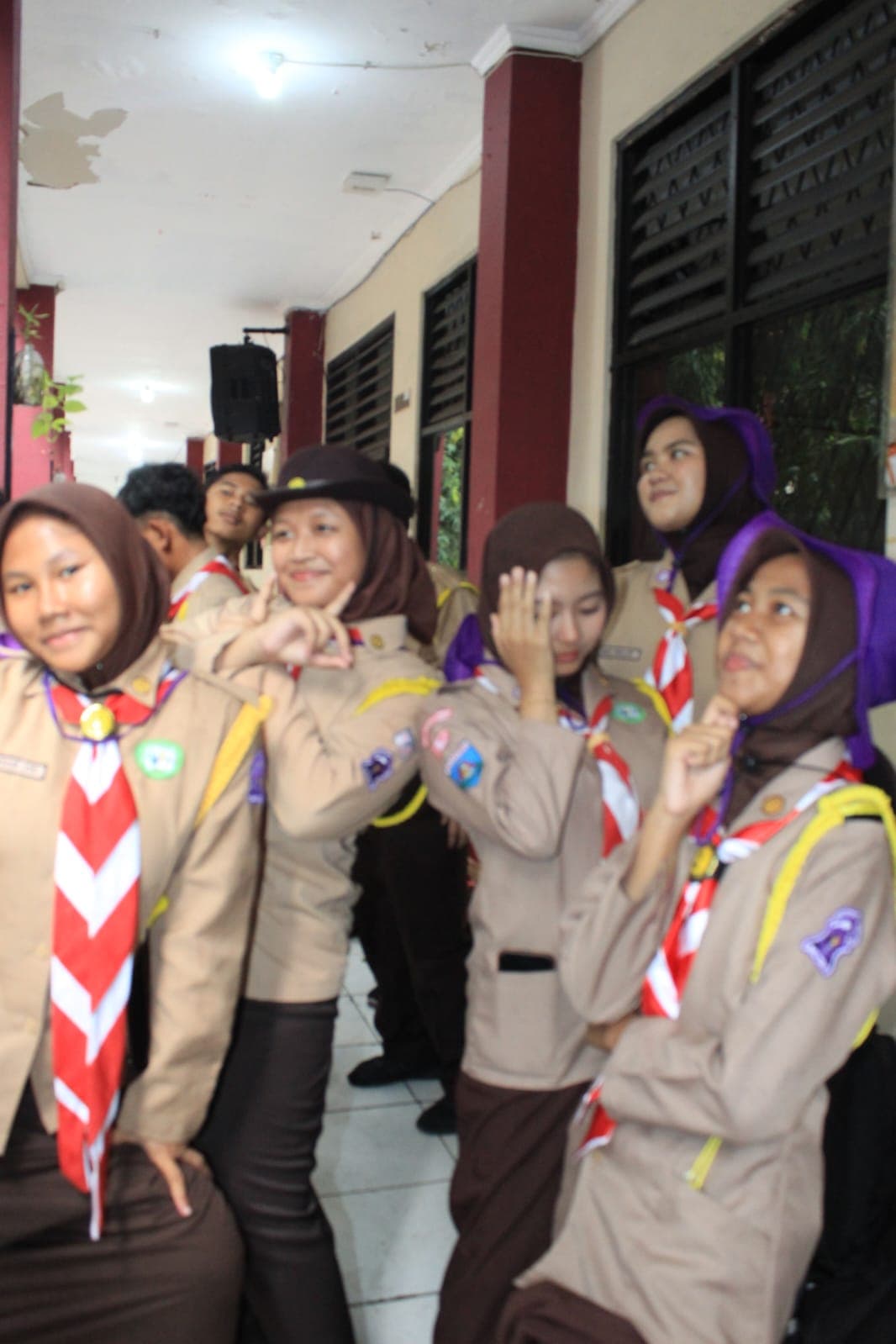Sekelompok pelajar Indonesia mengenakan seragam pramuka lengkap sedang berpose bersama di koridor sekolah.
